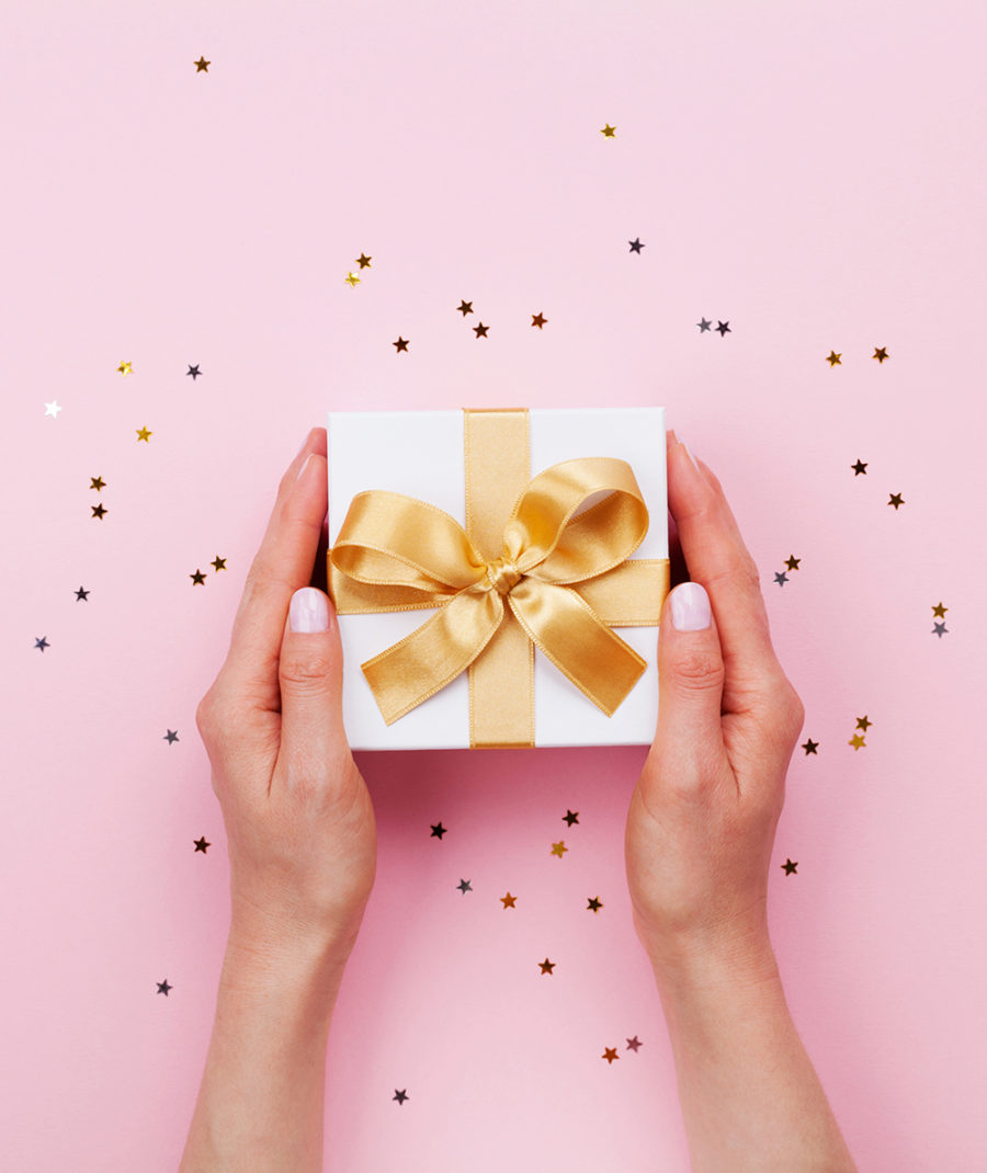 Womans hands holding gift or present box decorated confetti on p